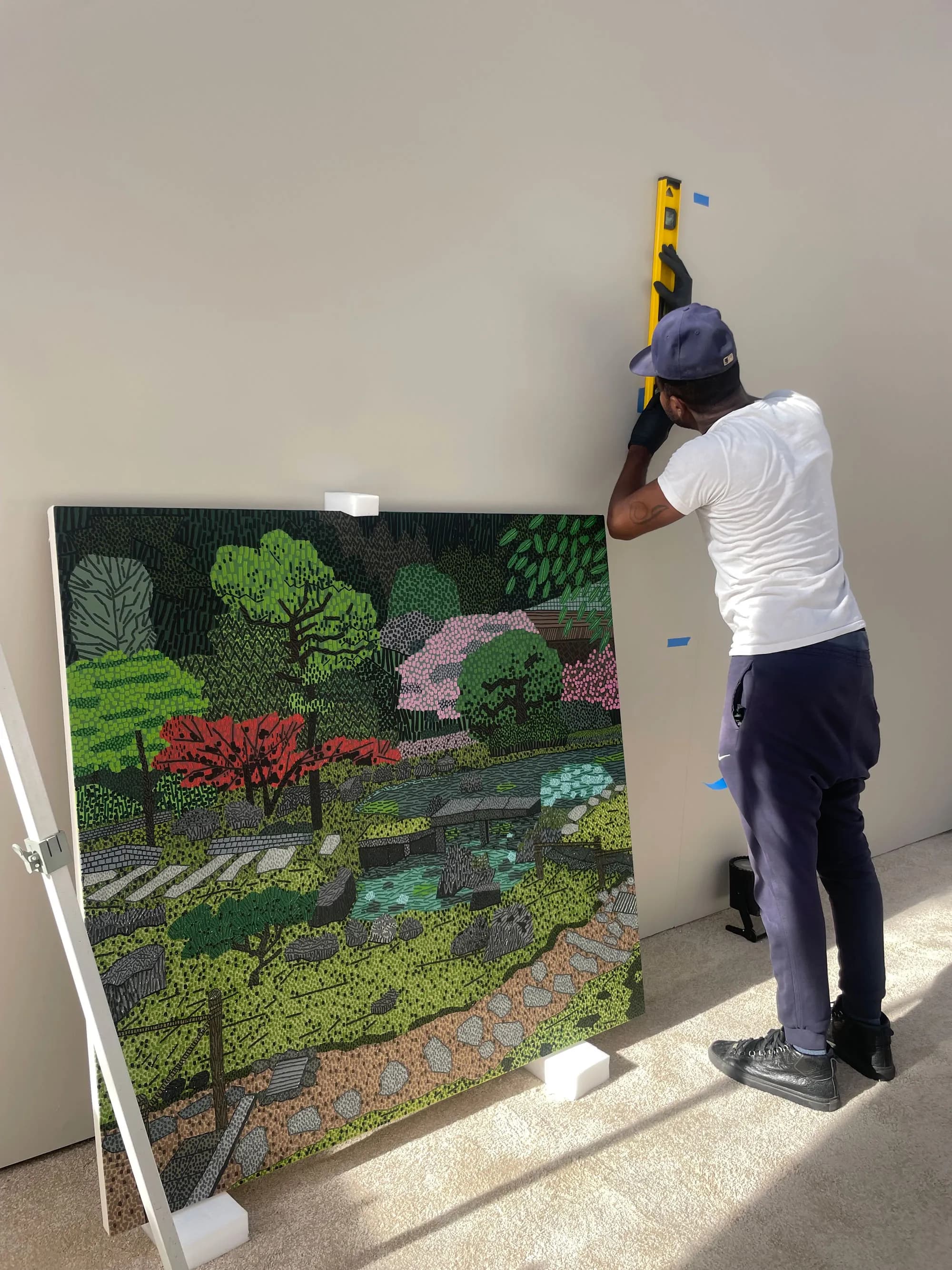 Handler leveling large landscape painting for installation