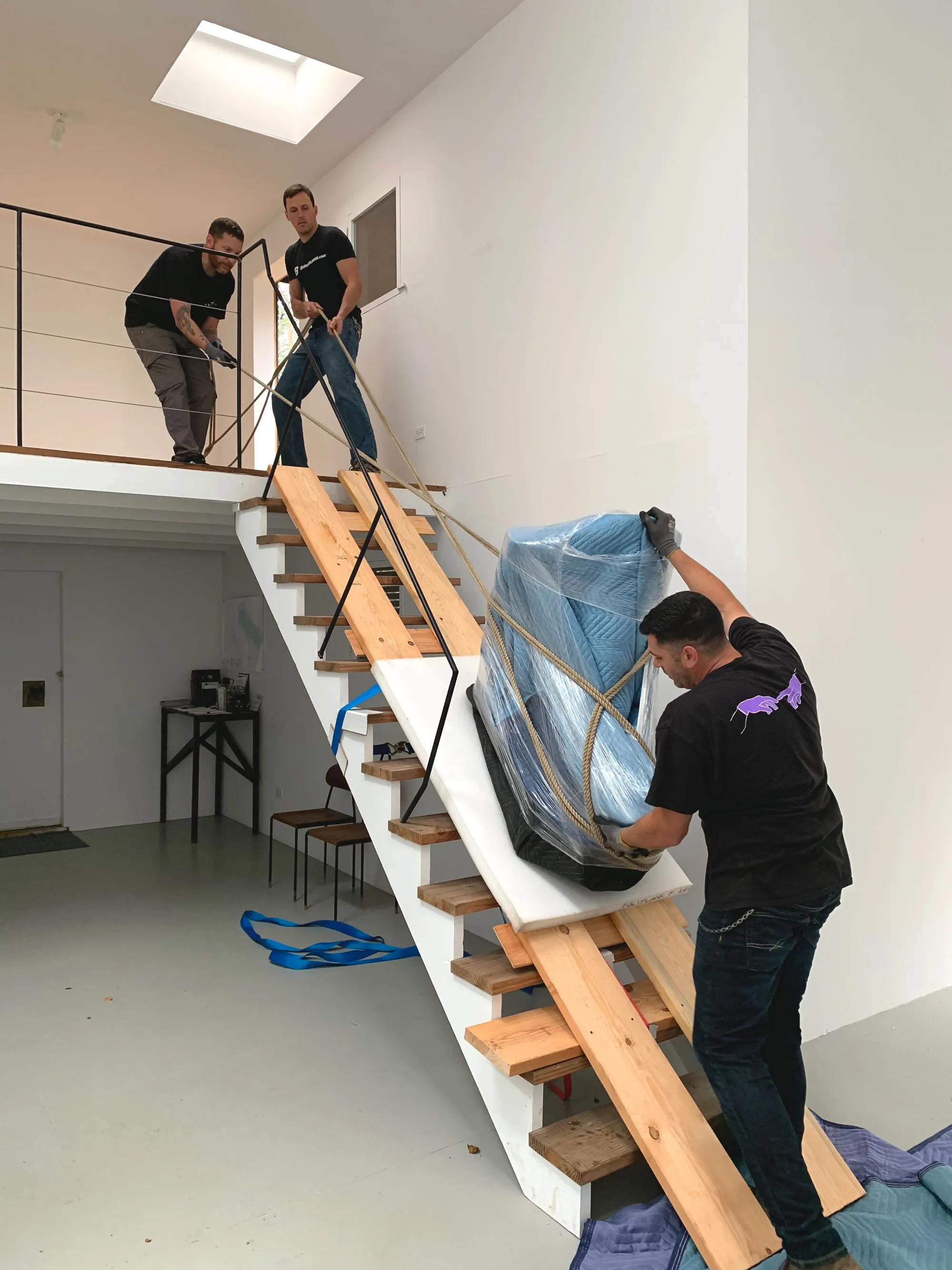 Crew carrying wrapped artwork down staircase with ropes