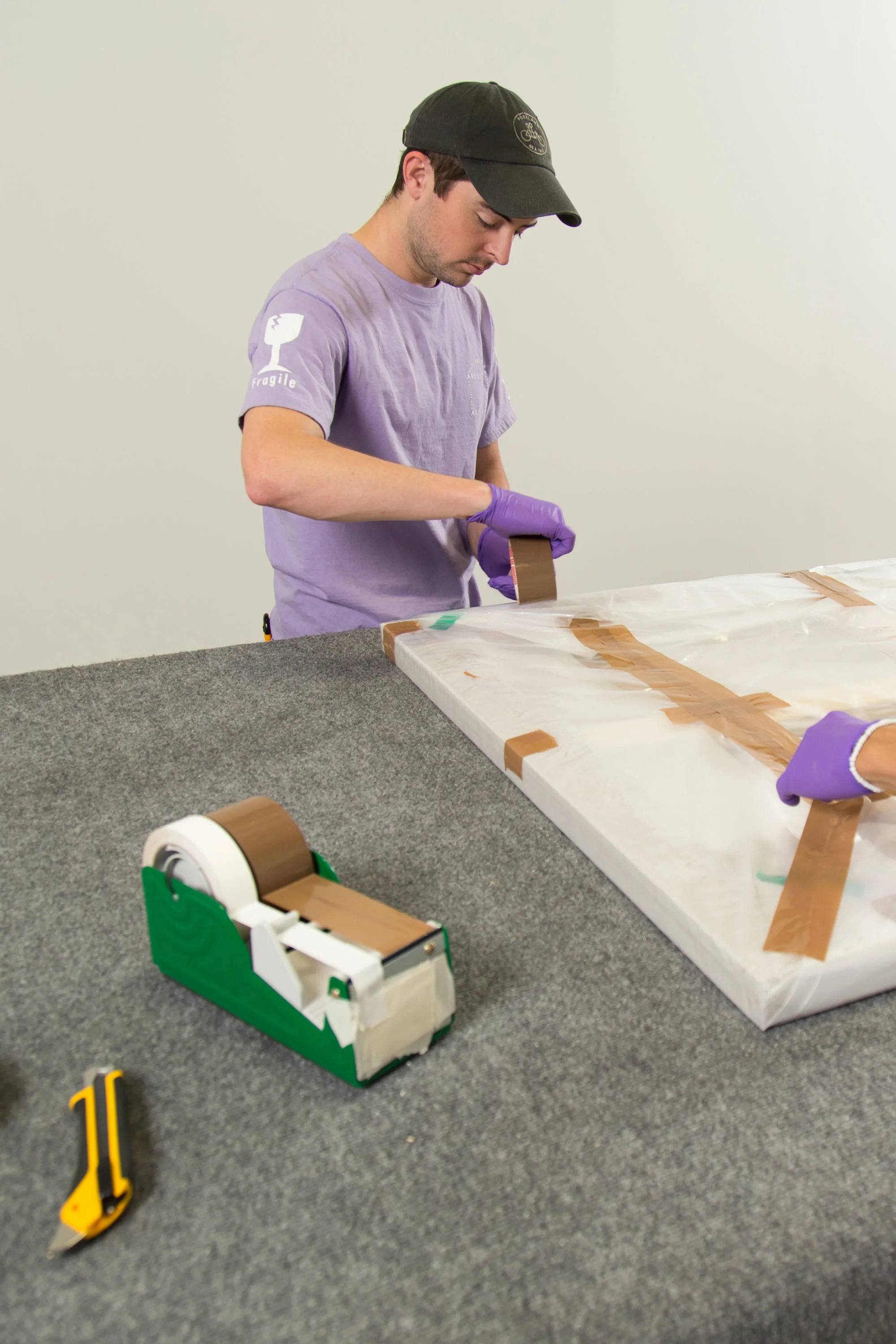 Worker taping wrapped artwork on padded table